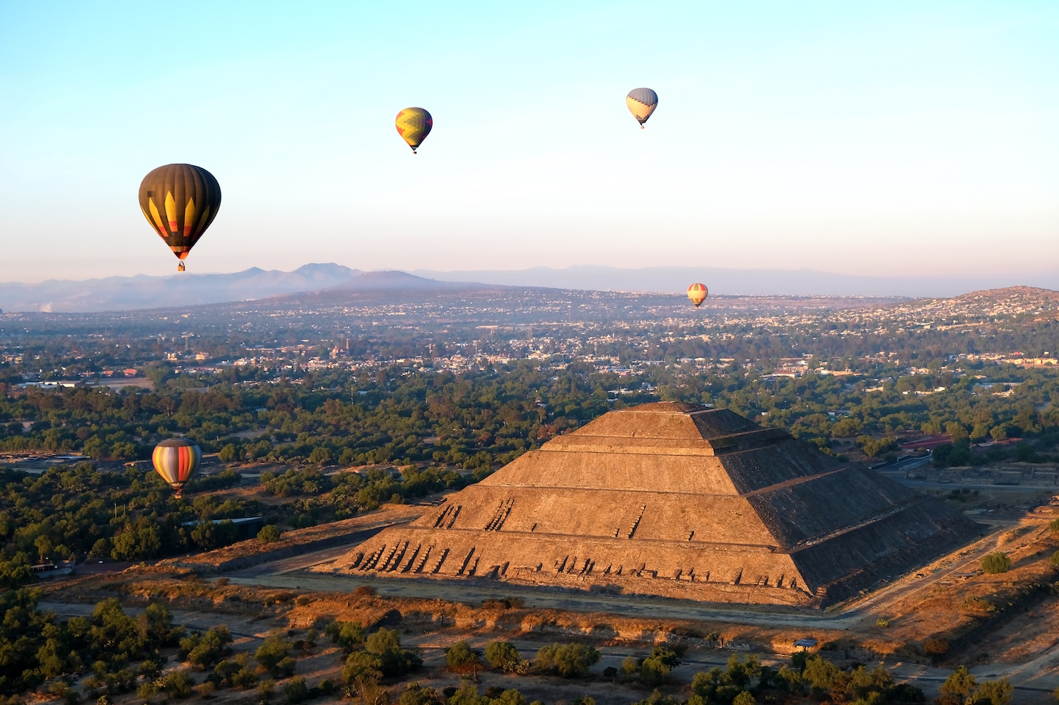 Teotihuacán pyramid at sunrise with hot-air balloons